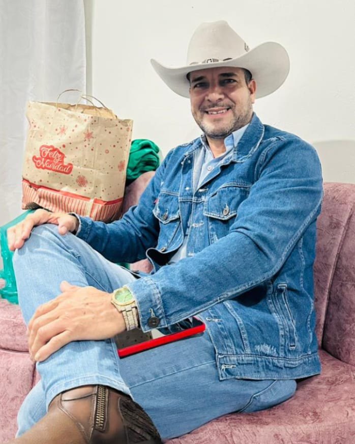 Cliente sonriente con sombrero blanco y chaqueta de mezclilla, sentado en un sofá