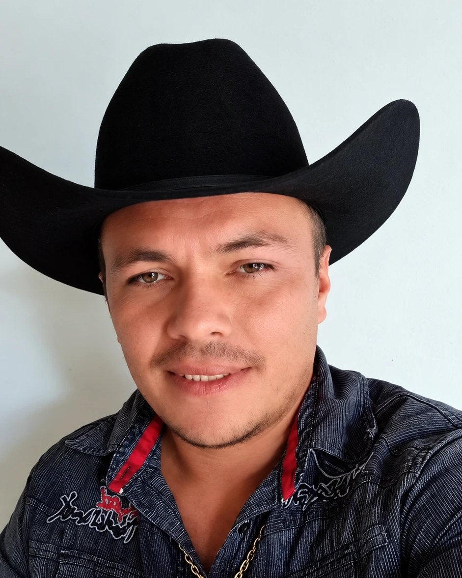 Cliente sonriente con sombrero negro y camisa oscura